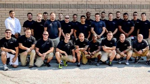 A group of men in black shirts and tan shorts.